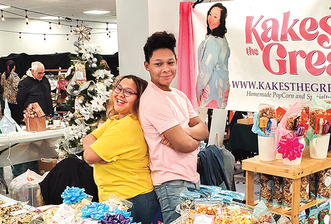 Two people posing for a photo while surrounded by an assortment of different kinds of popcorn