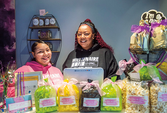 Two people surrounded by colorful bags of popcorn