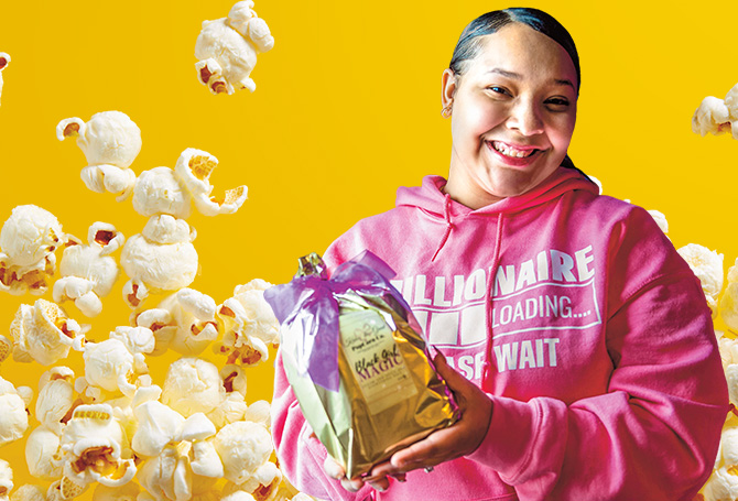 Person holding a bag of popcorn with a yellow popcorn background
