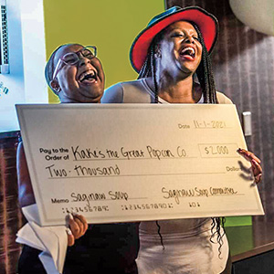 Two people holding a large check and smiling