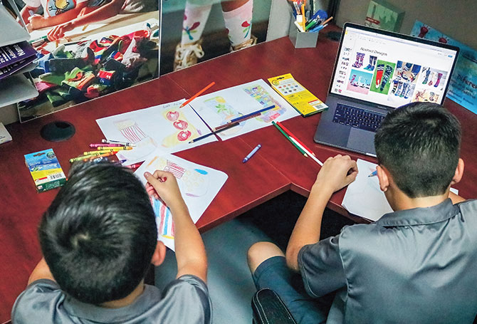 Two kids drawing with colored pencils at a desk