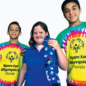 Two kids in shirts that read "Special Olympics Florida" standing next to a person holding socks